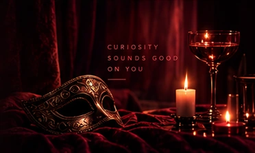 A gold masquerade mask, candlelight and a coupe glass.